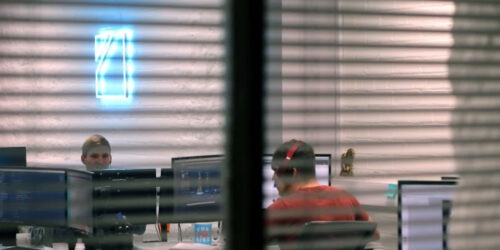 An image of an office, taken through a set of blinds