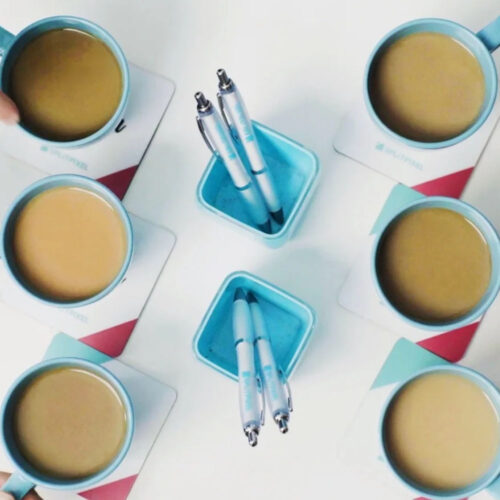 Six cups of tea and two pots with two pens in, taken from above