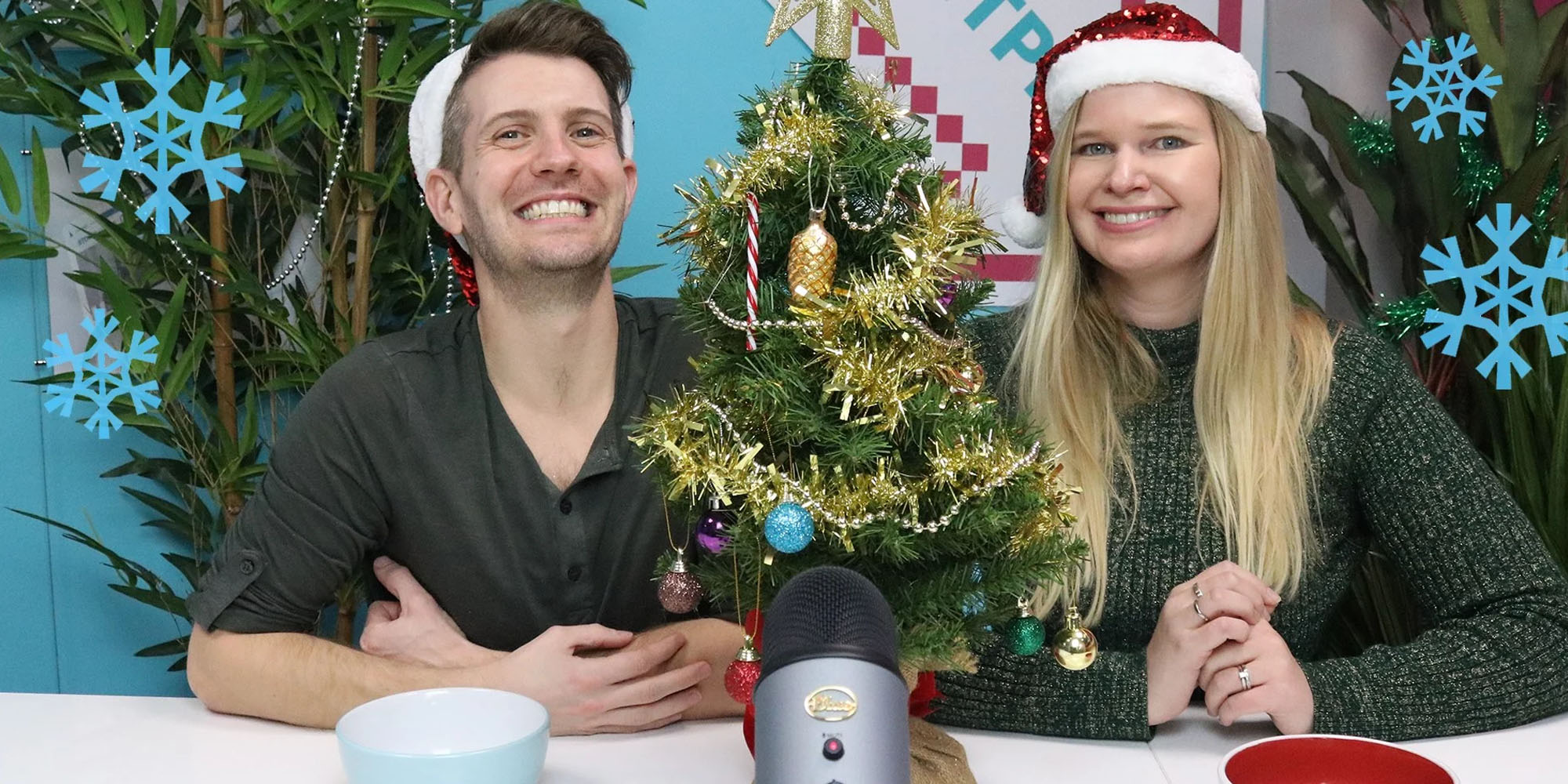 Rob and Amy wearing Santa hats, next to a small Christmas tree