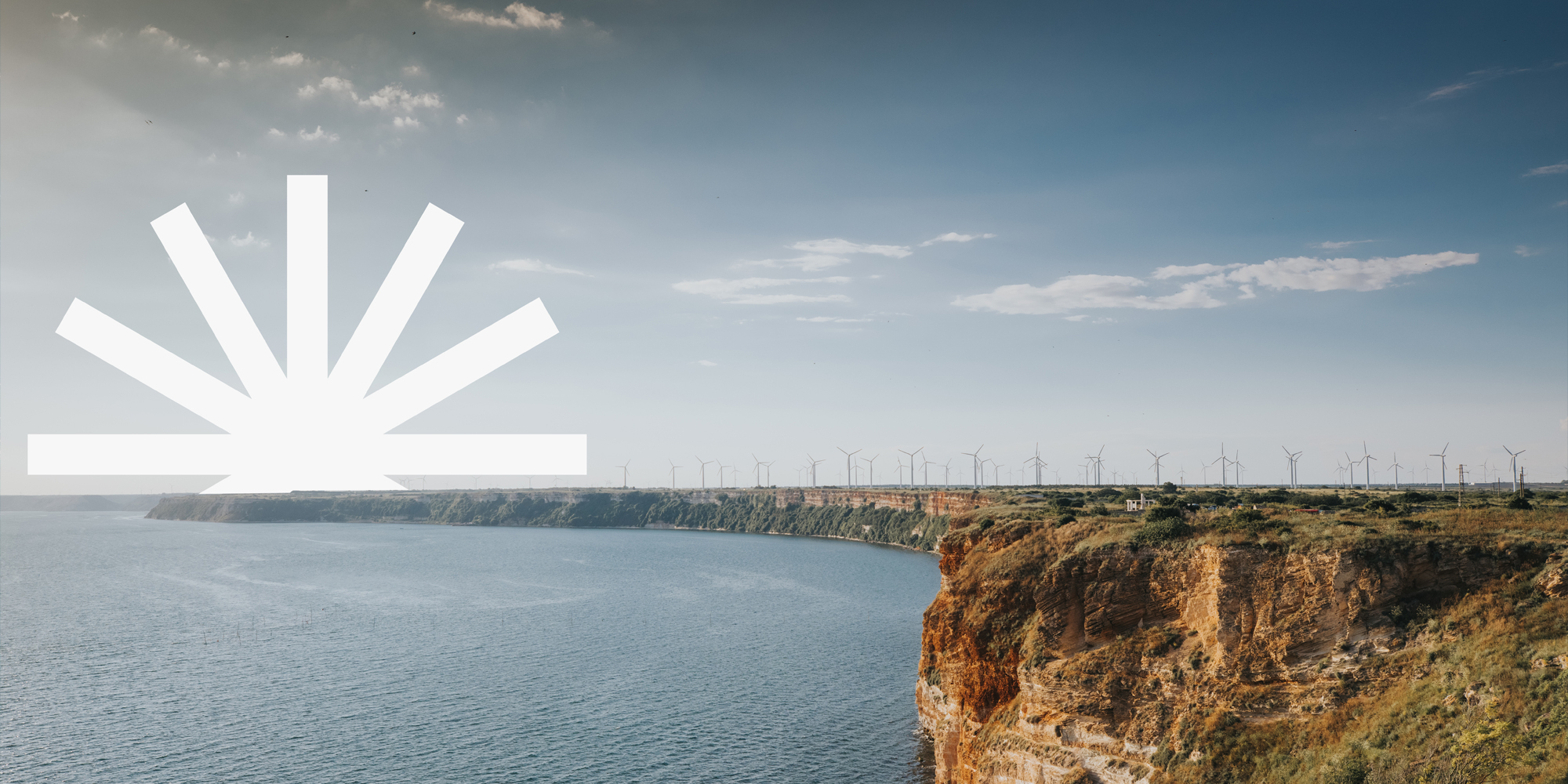 landscape image of some cliffs and a windfarm, with the Creative Climate logo over the cliffs