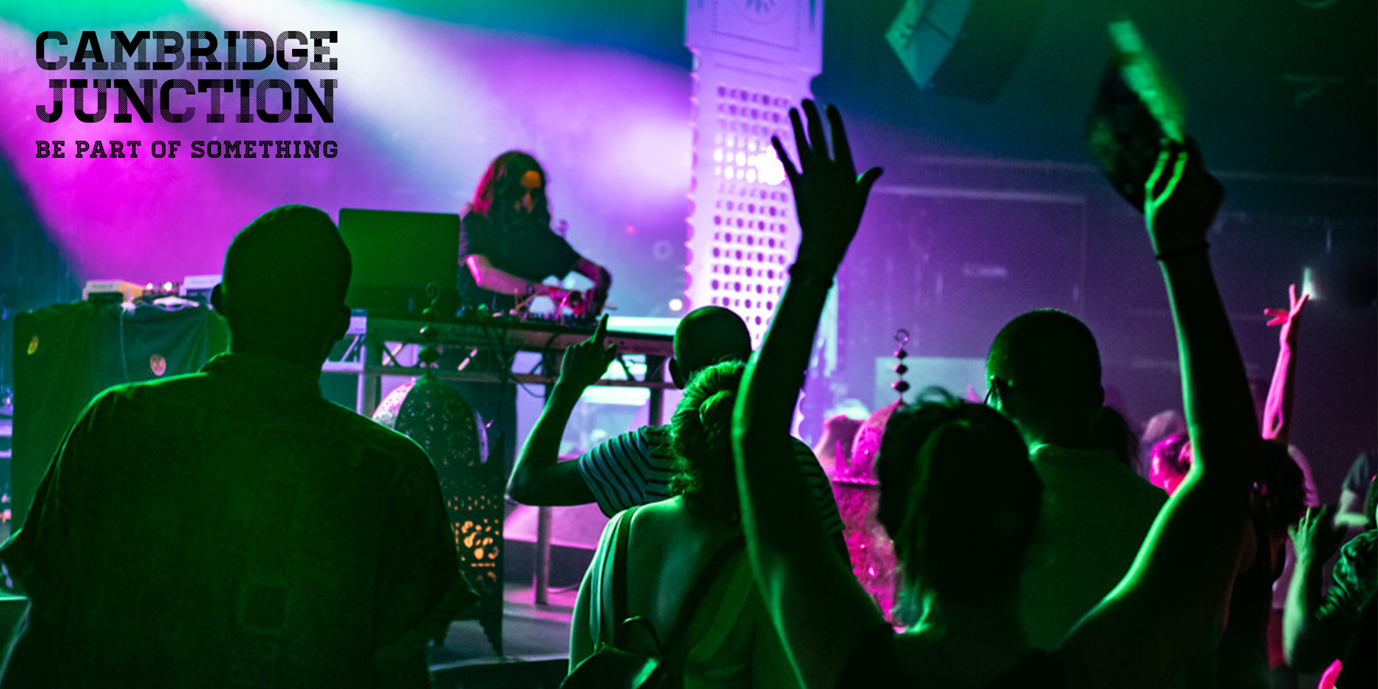 Image of a nightclub with people dancing in front of a DJ featuring Cambridge Junction logo