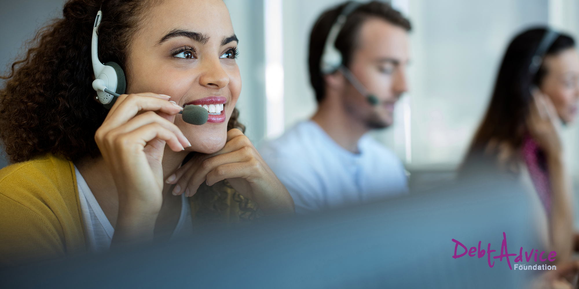 A Person wearing a headset smiling with the Debt Advice foundation logo in the bottom right corner