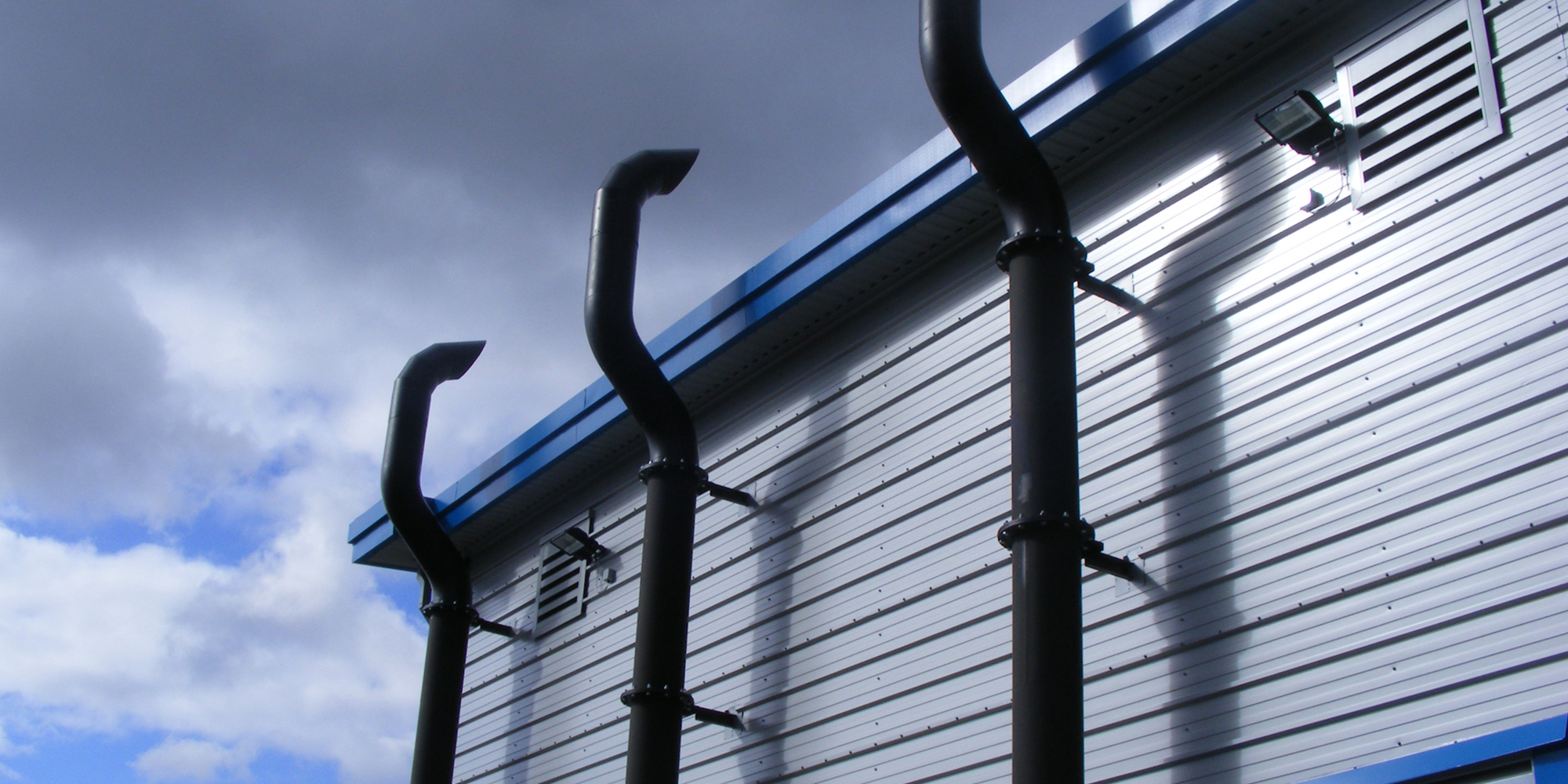 Side of a metal building showing three large pipes