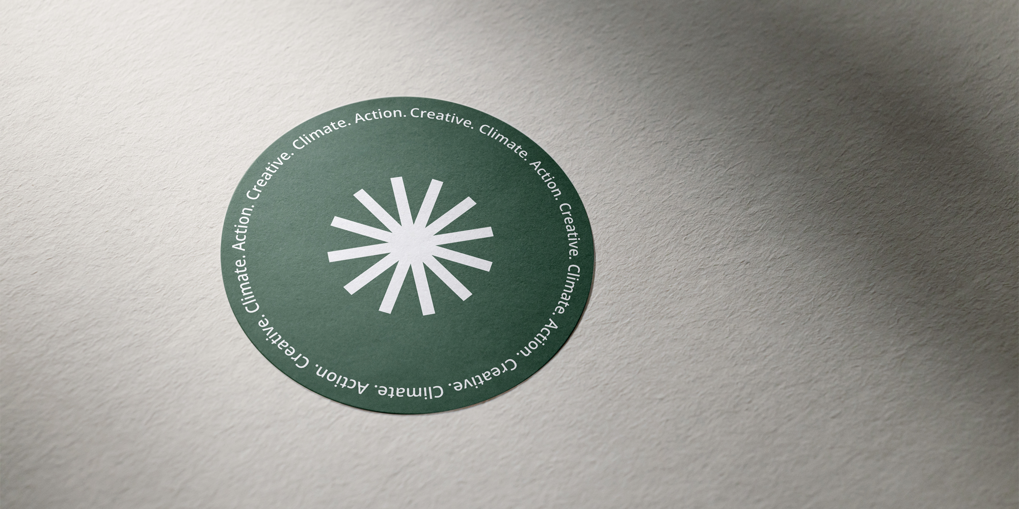 A green sticker with the Climate Creative logo on a piece of paper