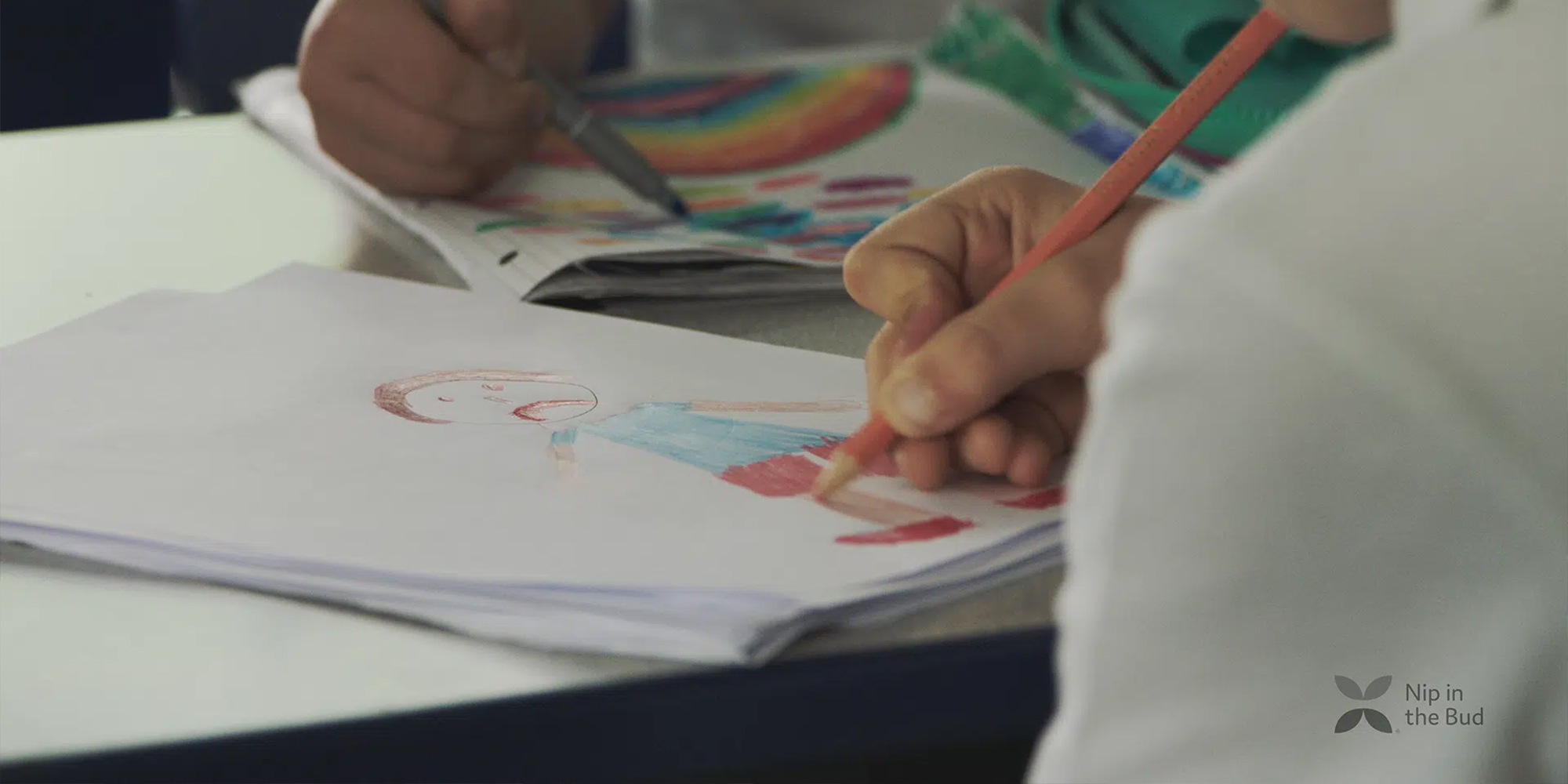 A child colouring a self portrait with the Nip In The Bud logo