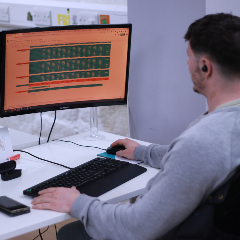 A man looking at a computer screen showing a spreadsheet