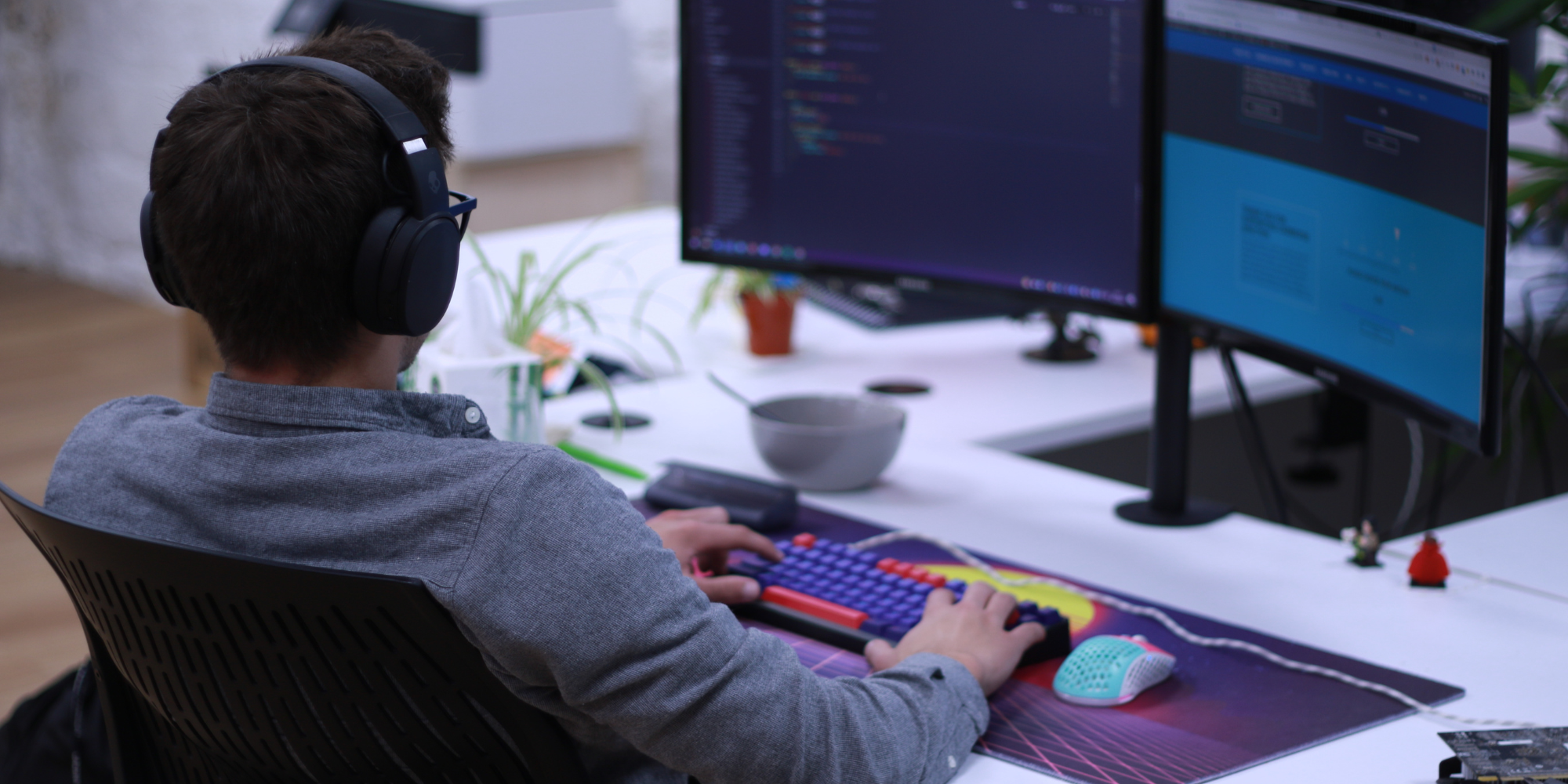 A man wearing headphones looking at two computer screens