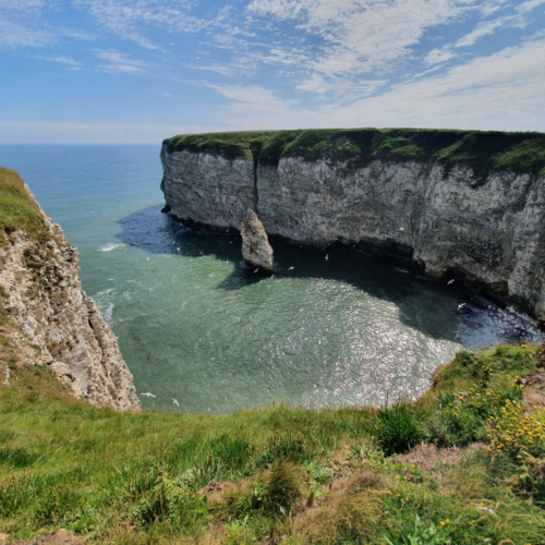 A Landscape photo of some white cliffs in a bay with the sea below